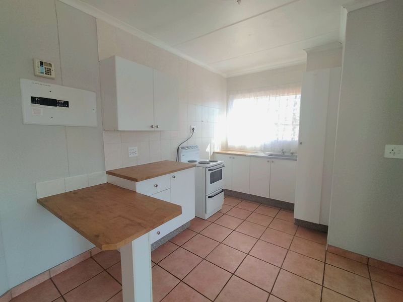A functional kitchen featuring white cabinetry, laminate countertops, a tiled backsplash, and a freestanding stove, offering a clean and practical workspace.