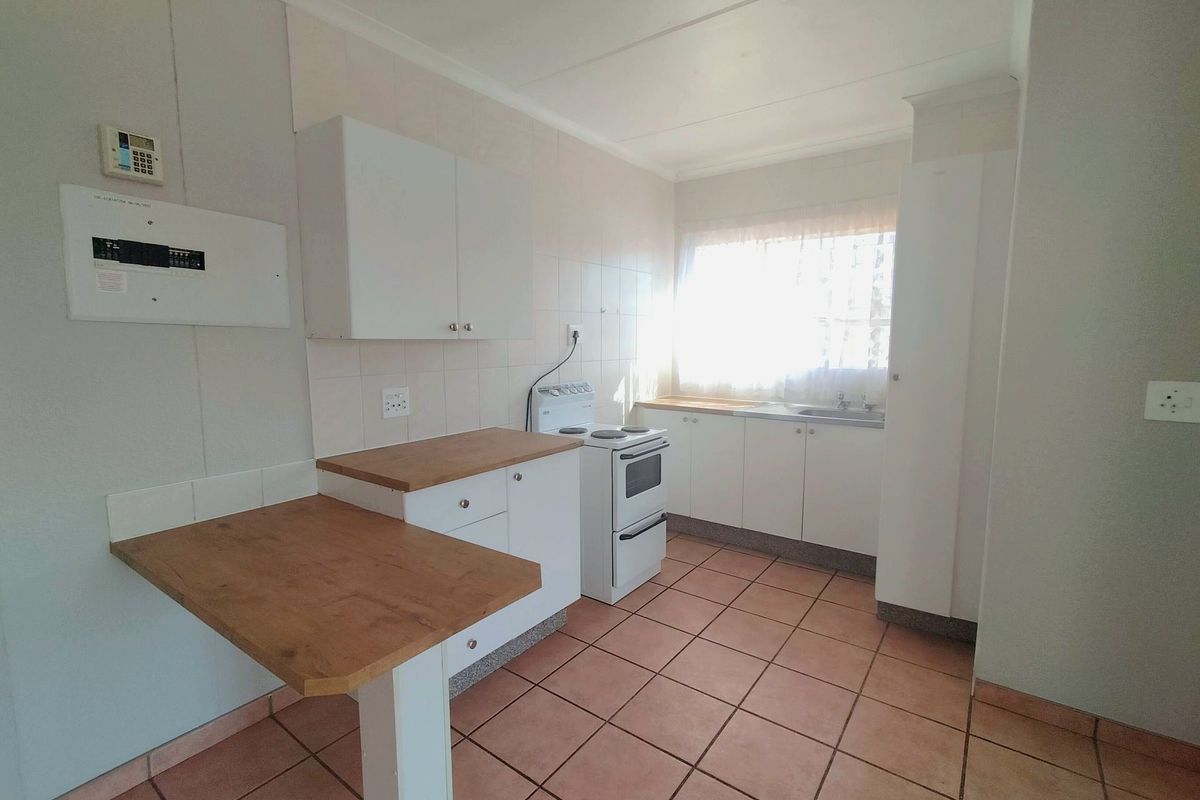 A functional kitchen featuring white cabinetry, laminate countertops, a tiled backsplash, and a freestanding stove, offering a clean and practical workspace.