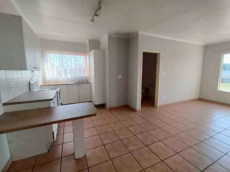 Open-plan living and kitchen area featuring tiled flooring, built-in cabinetry, and a functional layout with direct access to adjacent rooms.