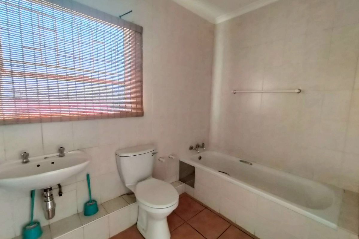 A functional bathroom featuring a pedestal washbasin, toilet, and a built-in bathtub with tiled walls and flooring.