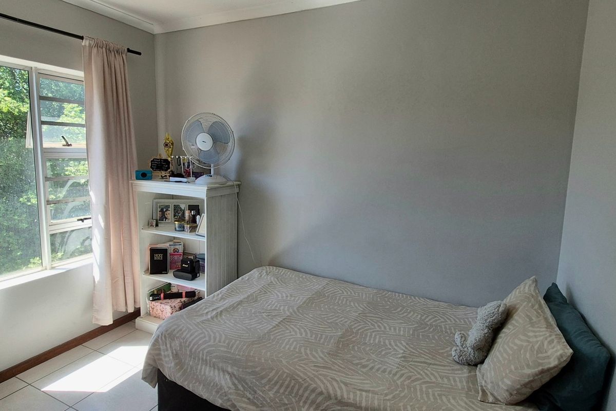 A functional bedroom featuring tiled flooring and a large window that provides natural light, offering a neutral canvas for personalization.