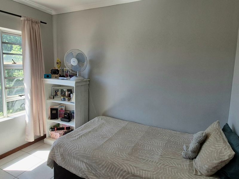 A functional bedroom featuring tiled flooring and a large window that provides natural light, offering a neutral canvas for personalization.