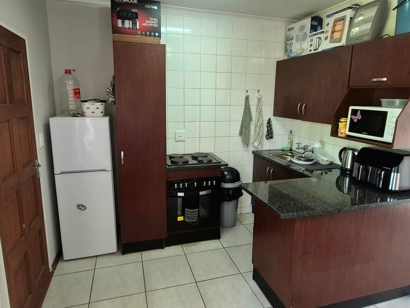 Compact kitchen featuring dark wood cabinetry, granite countertops, tiled backsplash, and built-in electric stove and oven.
