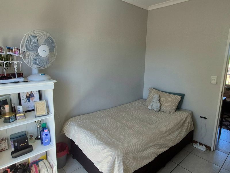 A functional bedroom featuring tiled flooring and neutral wall finishes, with direct access to an adjacent living area.
