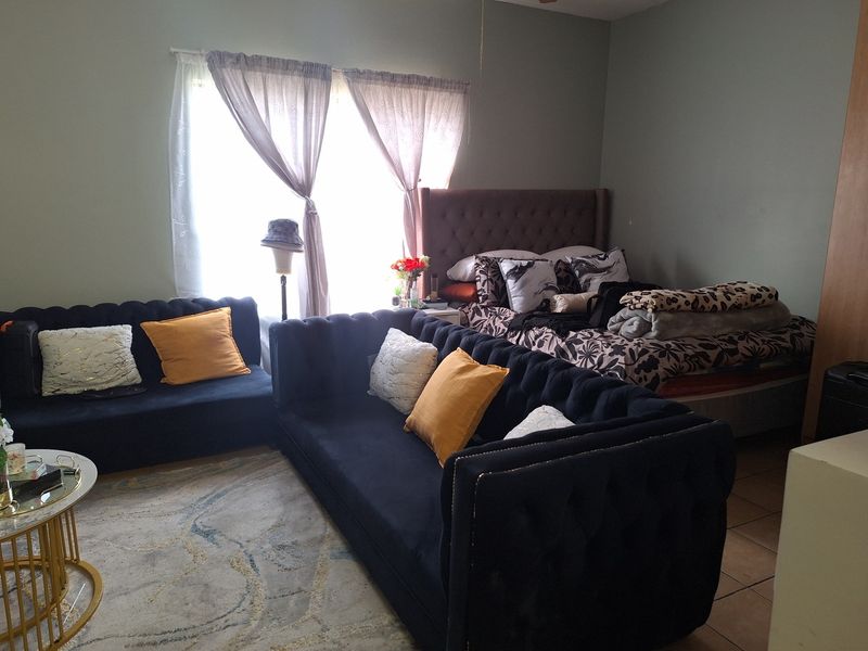 Open plan living and sleeping area featuring tiled flooring and natural light from a large window.
