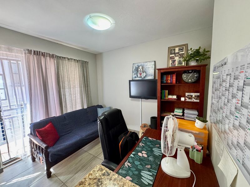 A functional home office space featuring tiled flooring and a sliding glass door providing natural light.