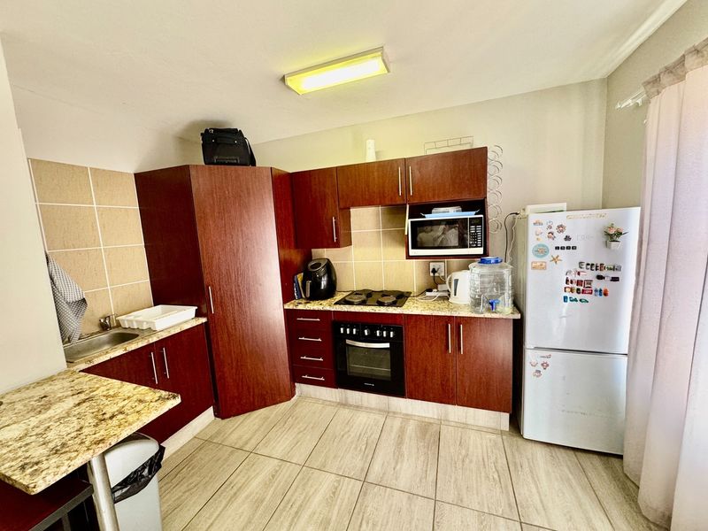 A functional kitchen featuring dark wood cabinetry, granite countertops, a built-in oven, gas hob, and tiled flooring.