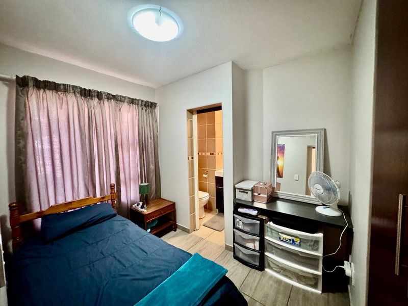 A bedroom featuring tiled flooring and direct access to an en-suite bathroom, providing a functional layout with built-in storage.