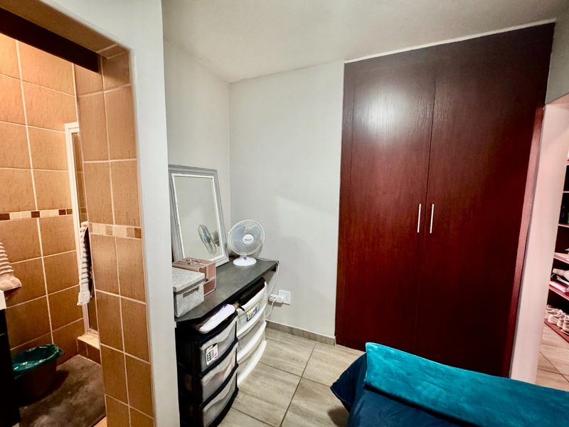 Bedroom featuring tiled flooring and a dark wood built-in wardrobe, with an adjacent tiled bathroom visible through the doorway.