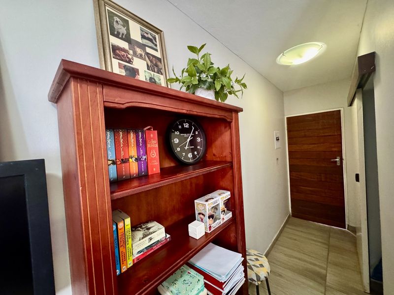 A functional hallway featuring tiled flooring, a wooden door, and a flush mount ceiling light.