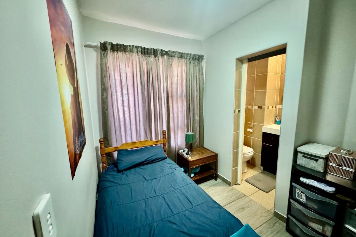 A compact bedroom featuring tiled flooring and an attached en-suite bathroom, providing a functional and private living space.