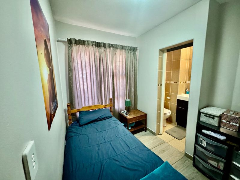 A compact bedroom featuring tiled flooring and an attached en-suite bathroom, providing a functional and private living space.