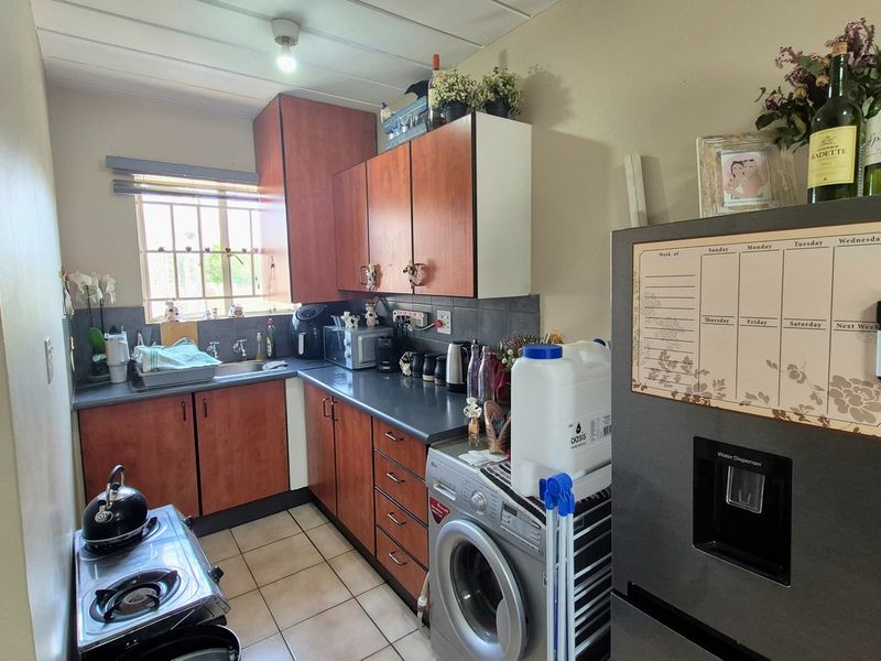Compact kitchen featuring laminate cabinetry, tiled flooring, and a functional layout with integrated space for laundry appliances.