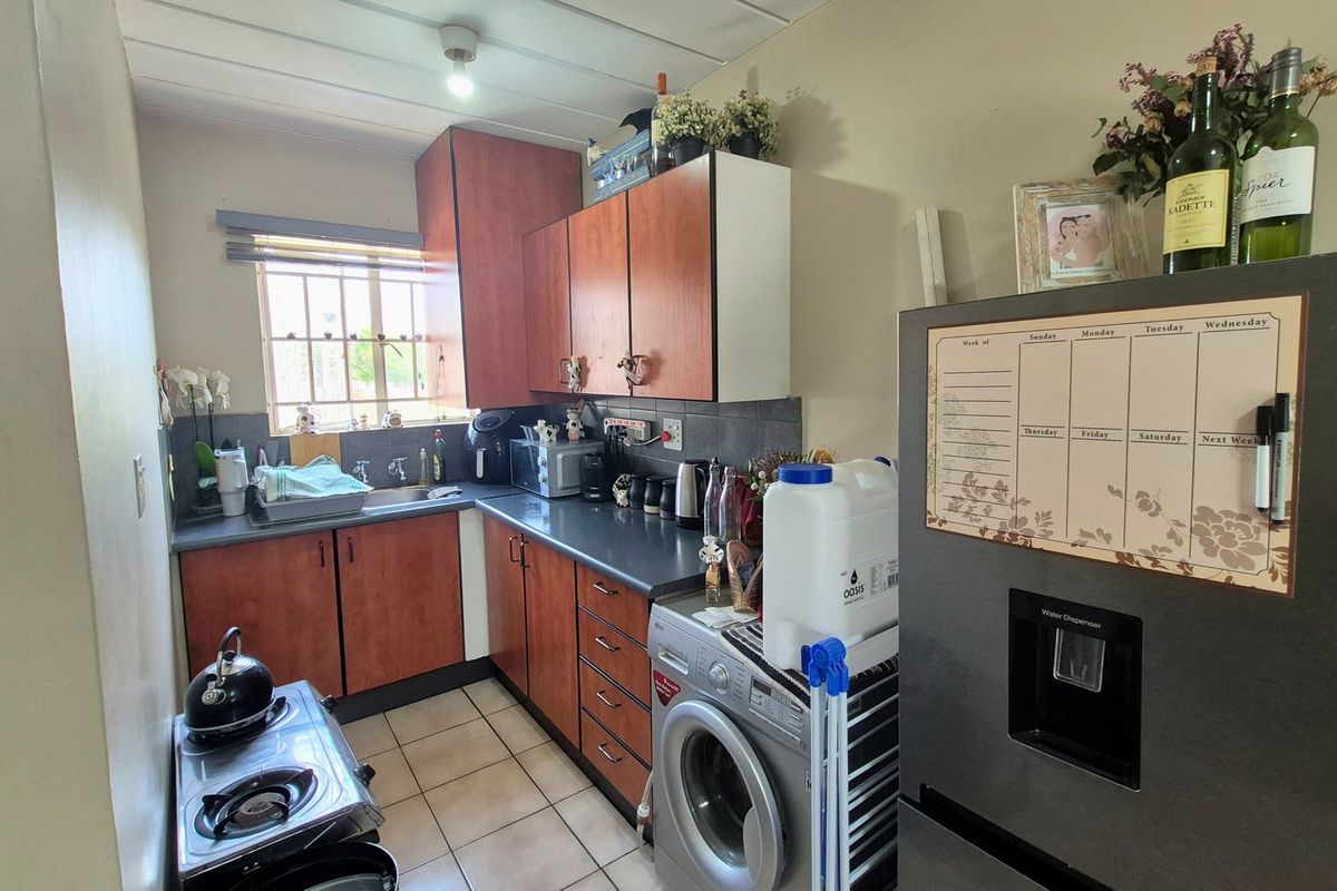 Compact kitchen featuring laminate cabinetry, tiled flooring, and a functional layout with integrated space for laundry appliances.
