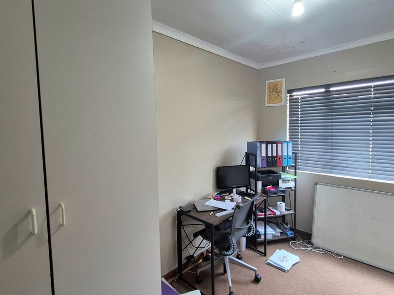 A bedroom featuring built-in cupboards, venetian blinds, and coving, showing visible signs of ceiling water damage.