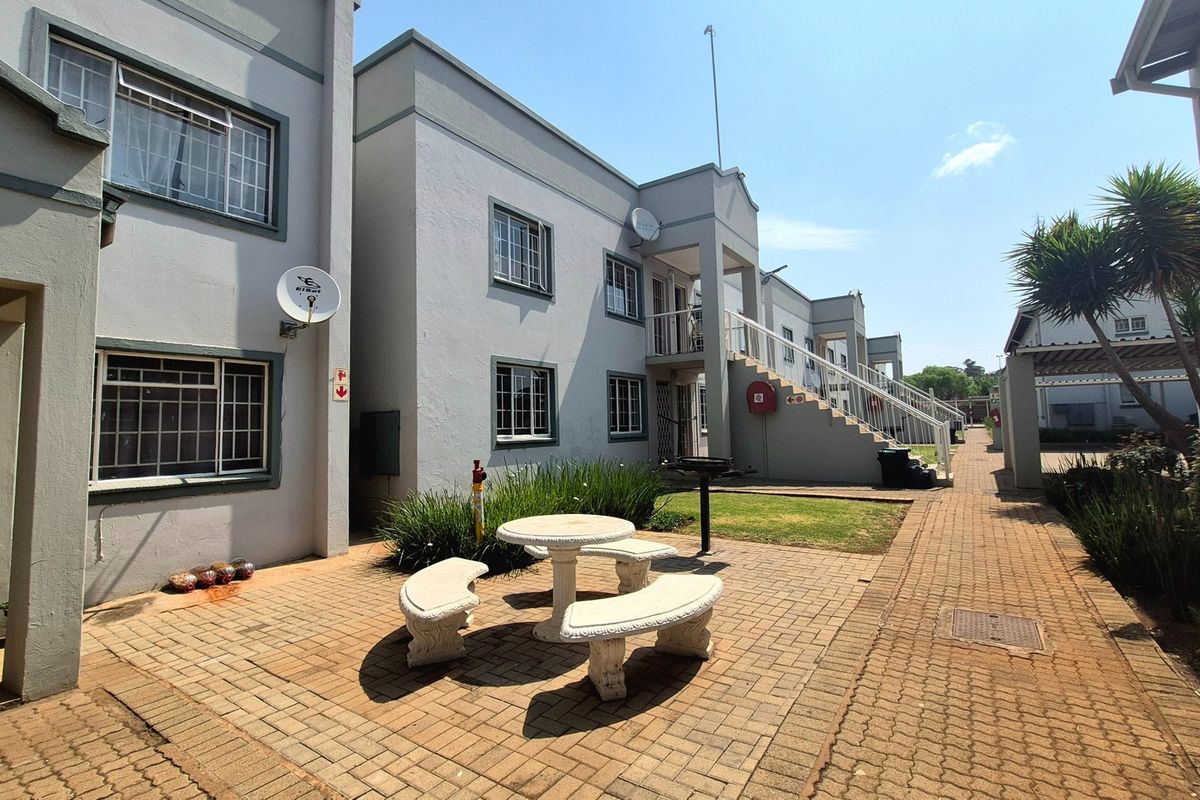 Exterior view of an apartment complex featuring a paved courtyard area, external staircases, and established building facades.