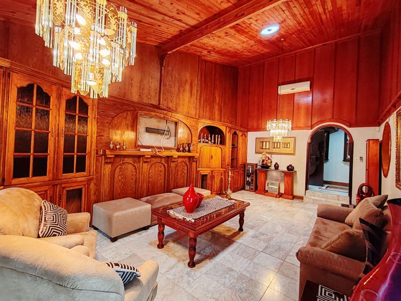 Spacious living room featuring extensive wood paneling, timber ceilings, marble flooring, and ornate built-in cabinetry with integrated crystal chandeliers.