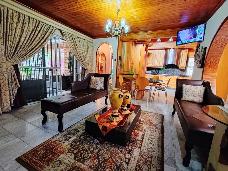 Open-plan living and kitchen area featuring a timber ceiling, tiled floors, and an archway leading to adjacent spaces.