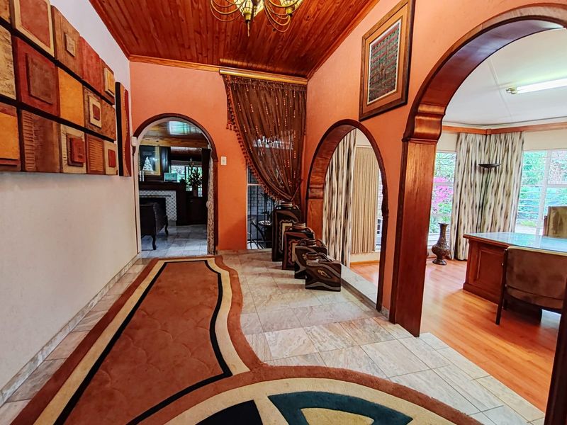 Spacious hallway featuring timber ceilings, arched architectural doorways, and tiled flooring, providing access to multiple living areas within the home.