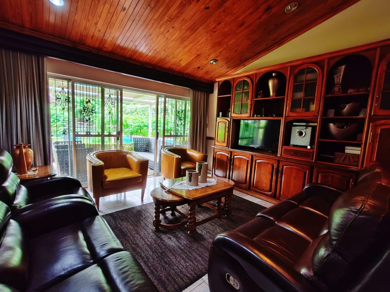 Spacious living room featuring a warm timber-clad vaulted ceiling, extensive built-in wooden cabinetry, and sliding glass doors providing access to the outdoor patio area.