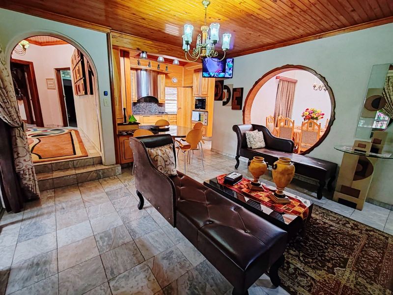 Open-plan living and kitchen area featuring timber ceilings, tiled floors, and a distinctive circular architectural opening connecting to the dining space.