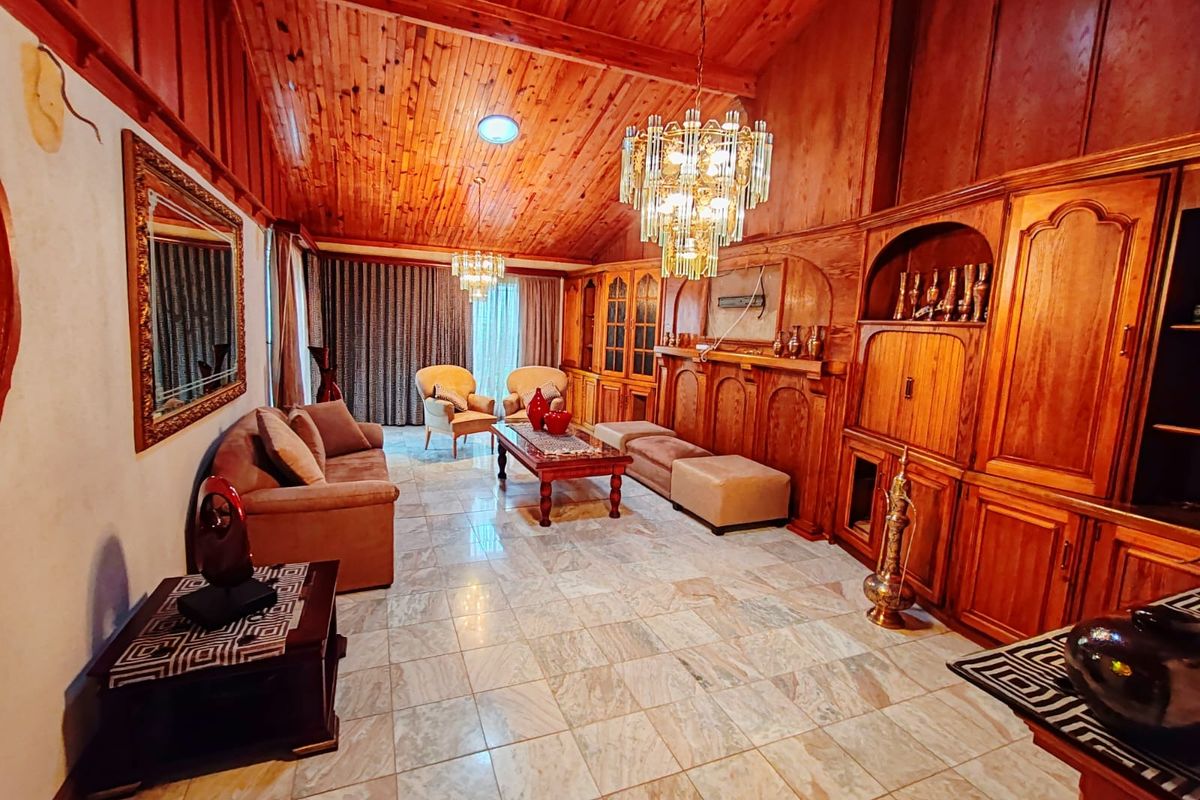 Spacious living room featuring vaulted timber ceilings, extensive built-in timber cabinetry, and marble tile flooring, offering a classic aesthetic with potential for modernization.