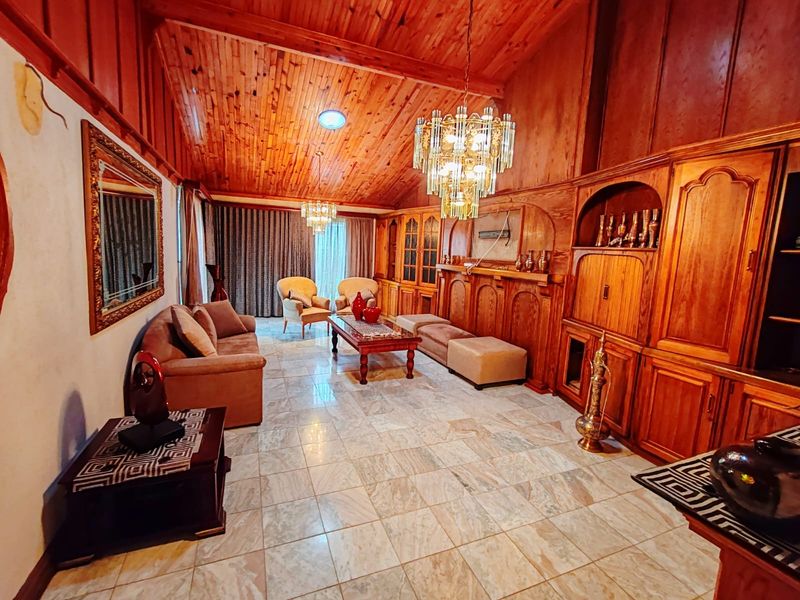 Spacious living room featuring vaulted timber ceilings, extensive built-in timber cabinetry, and marble tile flooring, offering a classic aesthetic with potential for modernization.