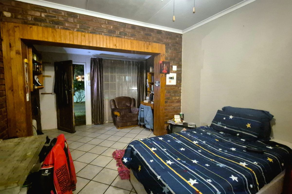 Bedroom featuring exposed brick walls, timber door framing, and tiled flooring, with direct access to an outdoor area.