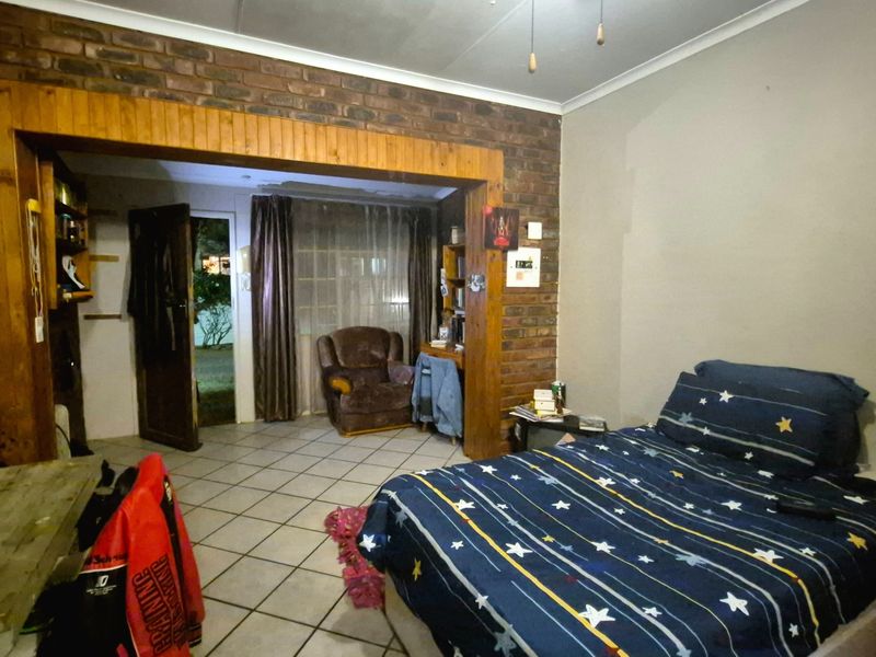 Bedroom featuring exposed brick walls, timber door framing, and tiled flooring, with direct access to an outdoor area.