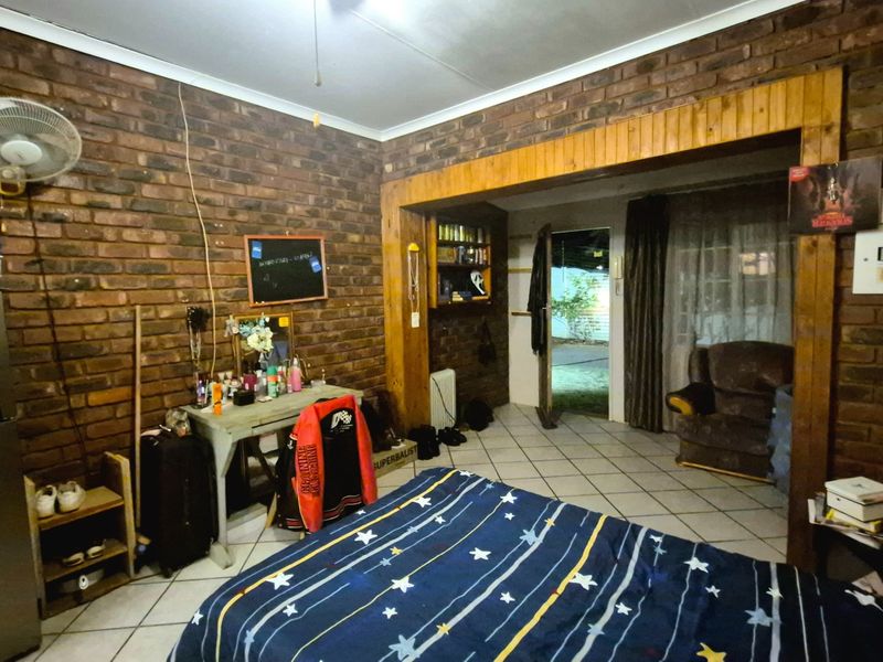 Bedroom featuring exposed brick walls, tiled flooring, and direct access to an outdoor area through a timber-framed doorway.