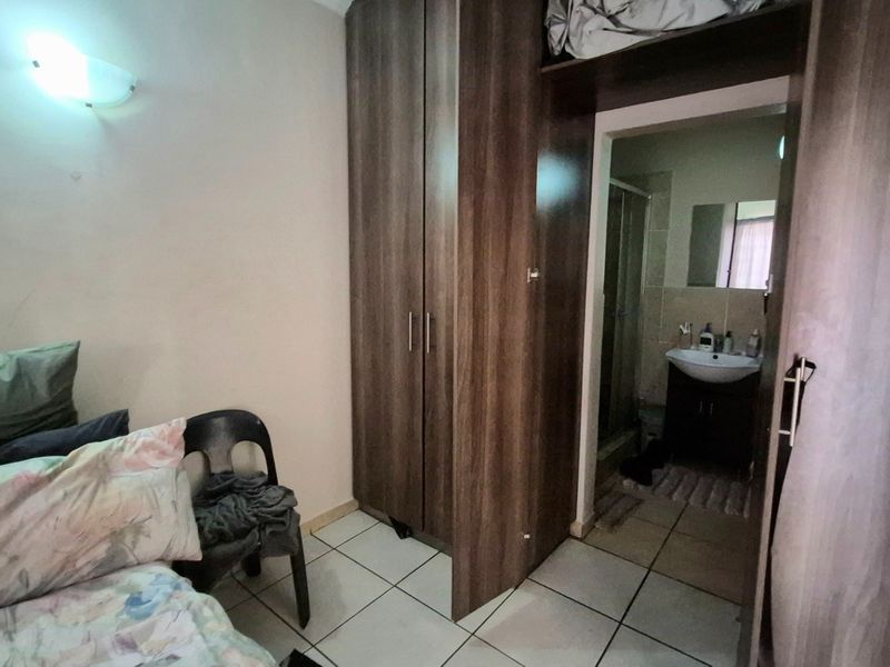 A bedroom featuring tiled flooring, a built-in wooden wardrobe, and direct access to an en-suite bathroom.