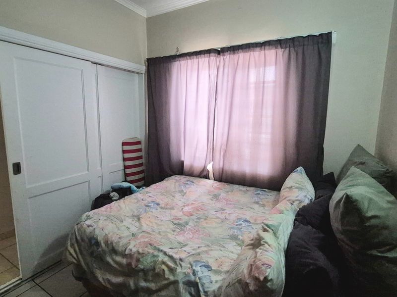 A bedroom featuring tiled flooring and a built-in sliding door wardrobe, providing functional storage space.
