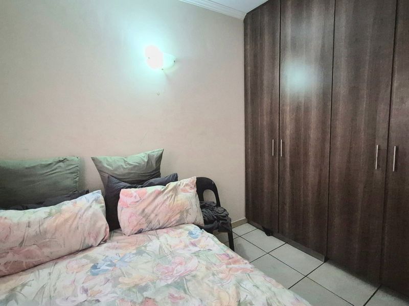 A bedroom featuring built-in wooden cupboards and tiled flooring, providing functional storage space.