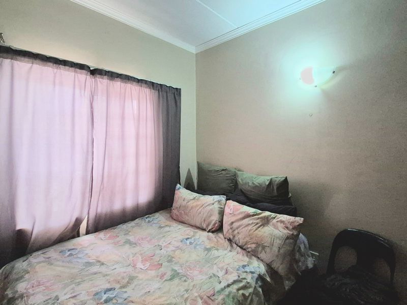 A standard bedroom featuring a wall-mounted light fixture and decorative cornice detailing.