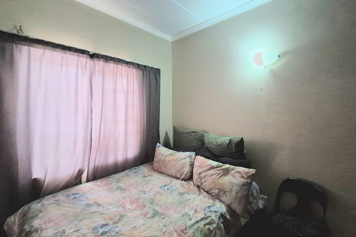 A standard bedroom featuring a wall-mounted light fixture and decorative cornice detailing.