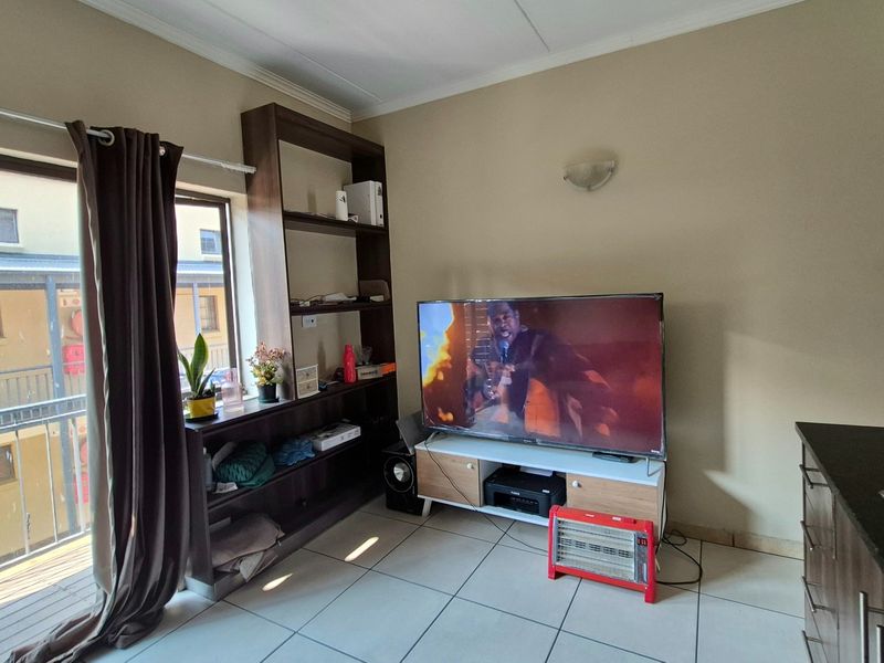 Open-plan living area featuring tiled floors, built-in shelving, and direct access to a balcony through a sliding glass door.