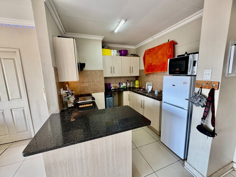 Functional kitchen featuring granite countertops, laminate cabinetry, a breakfast bar, and tiled flooring, offering a practical layout for daily meal preparation.