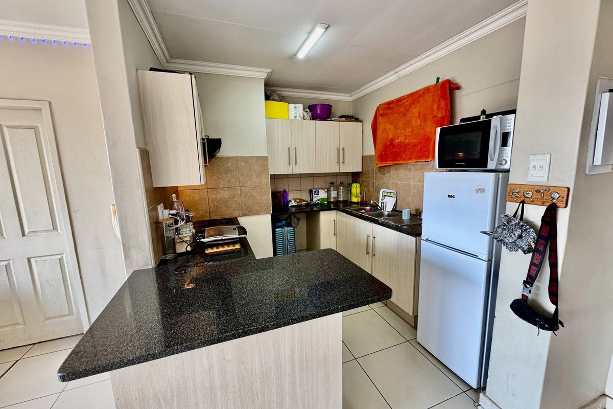 Functional kitchen featuring granite countertops, laminate cabinetry, a breakfast bar, and tiled flooring, offering a practical layout for daily meal preparation.