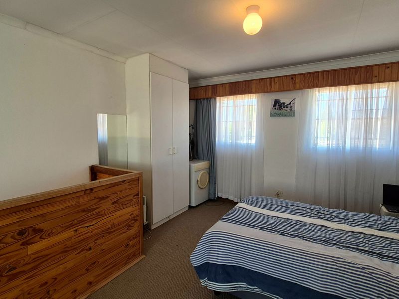 A bedroom featuring built-in wardrobes, timber detailing, and carpet flooring, offering a functional space with potential for modern updates.
