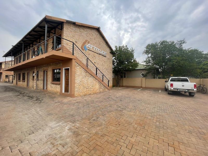 Exterior view of a face brick apartment building featuring an external staircase, balcony, and paved parking area.