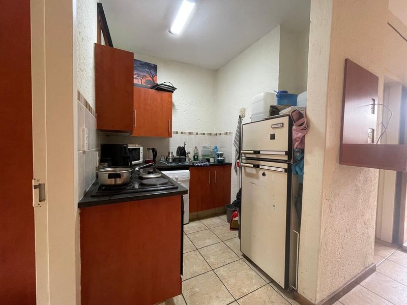 Compact kitchen featuring built-in cabinetry, tiled backsplash, and electric hob, offering a functional layout with potential for modernization.
