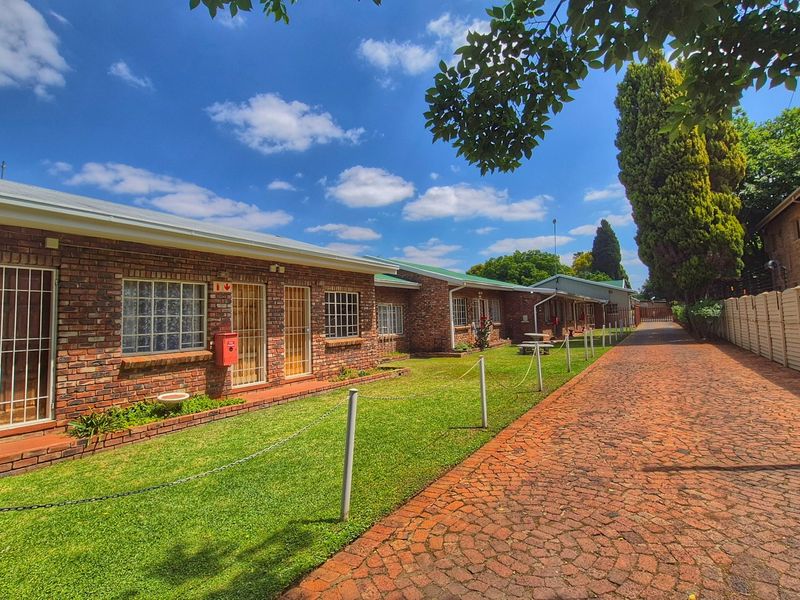 A well-maintained apartment complex exterior featuring face brick facades, secure gated entrances, a paved driveway, and neatly landscaped lawn areas.