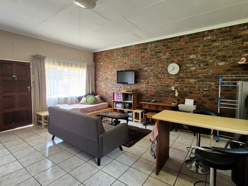Open-plan living area featuring a prominent exposed brick wall, ceramic tiled flooring, and a functional breakfast bar layout.