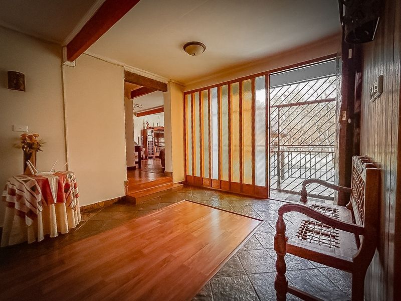 Entrance hall featuring a combination of tiled and laminate flooring, timber wall paneling, and a secure glass sliding door leading to the exterior.