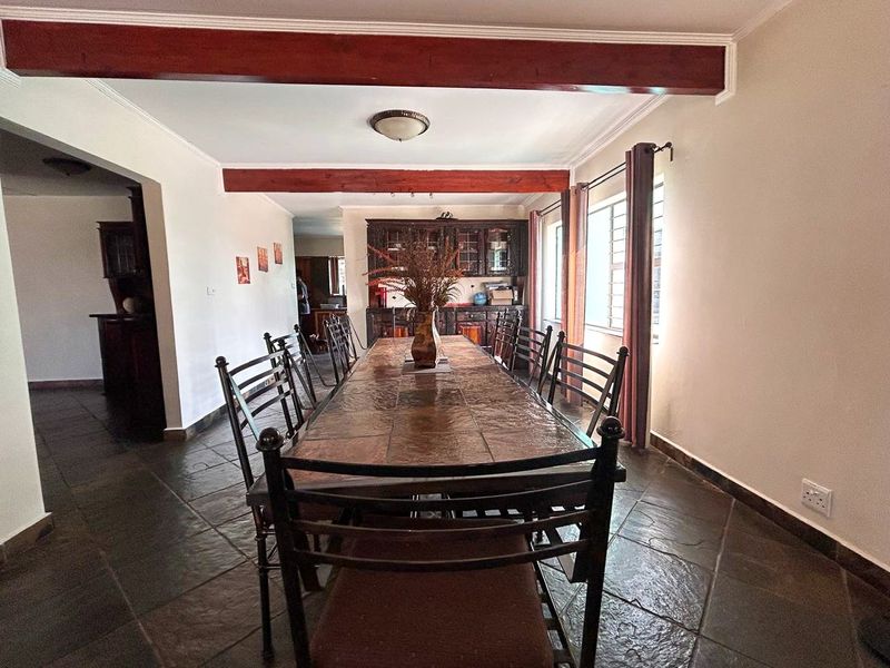 Spacious dining room featuring exposed timber ceiling beams, dark tiled flooring, and built-in wooden cabinetry, offering a warm and traditional aesthetic.