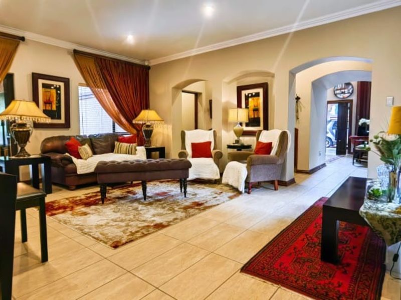 Spacious living room featuring tiled flooring, recessed lighting, and elegant archways leading to adjacent areas, with large sliding doors providing natural light.