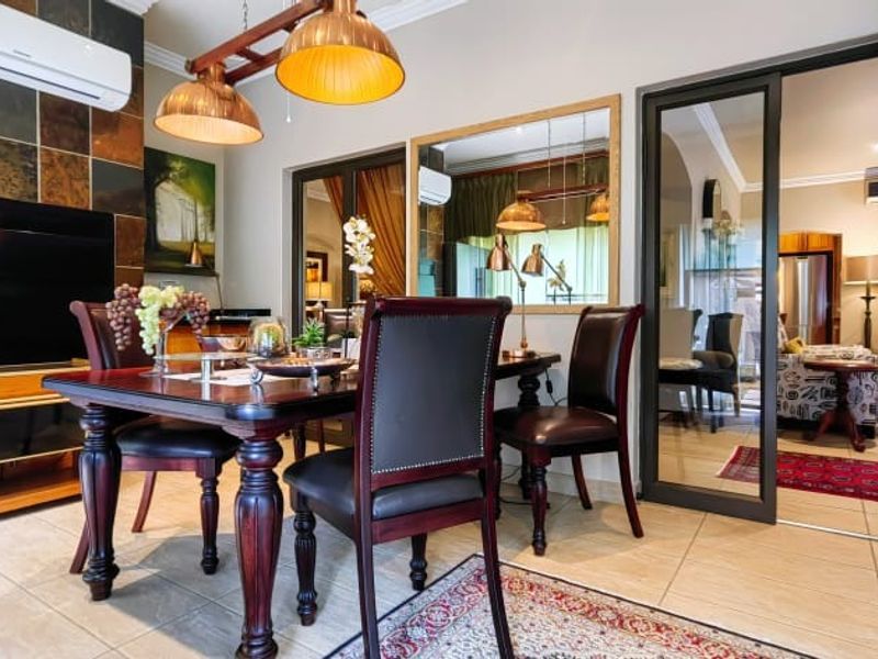 A well-maintained dining area featuring tiled flooring, a stone feature wall, and modern glass sliding doors leading to an adjacent living space.