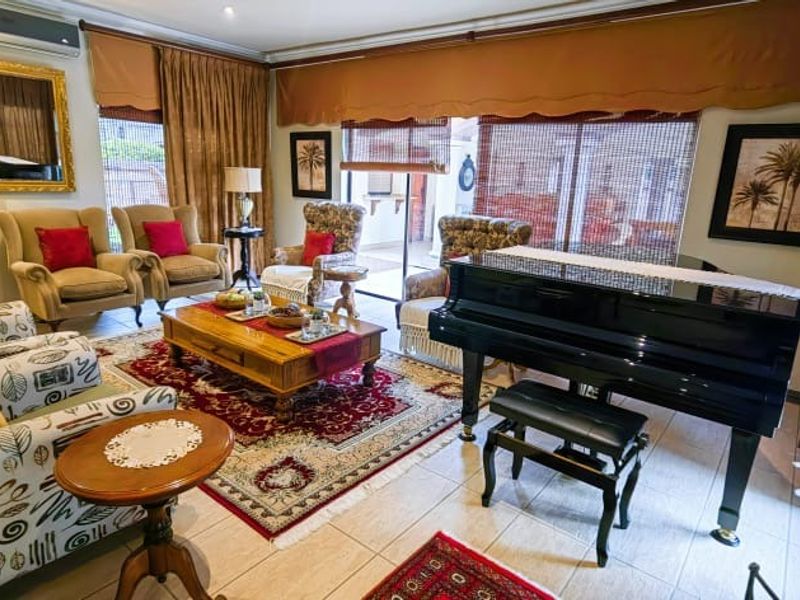 A spacious living room featuring tiled flooring, an integrated air conditioning unit, and large sliding glass doors providing access to the outdoor area.