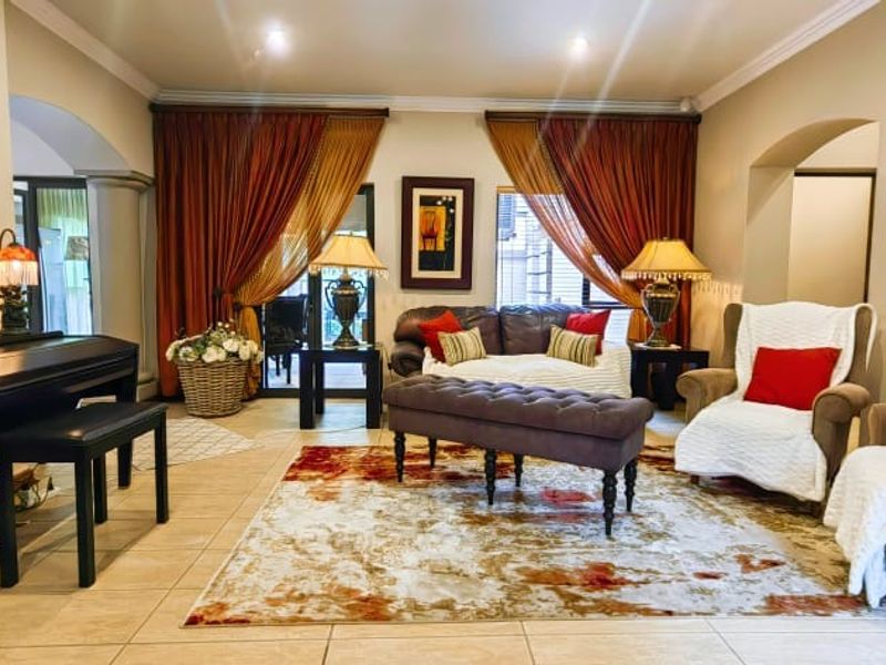 A spacious living room featuring tiled flooring, recessed lighting, and elegant archways, creating a comfortable and well-defined seating area.