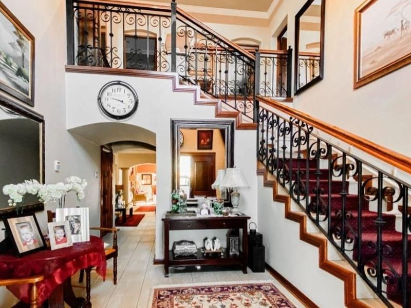 Grand entrance foyer featuring a prominent staircase with decorative wrought iron railings, tiled flooring, and an inviting archway leading into the home.
